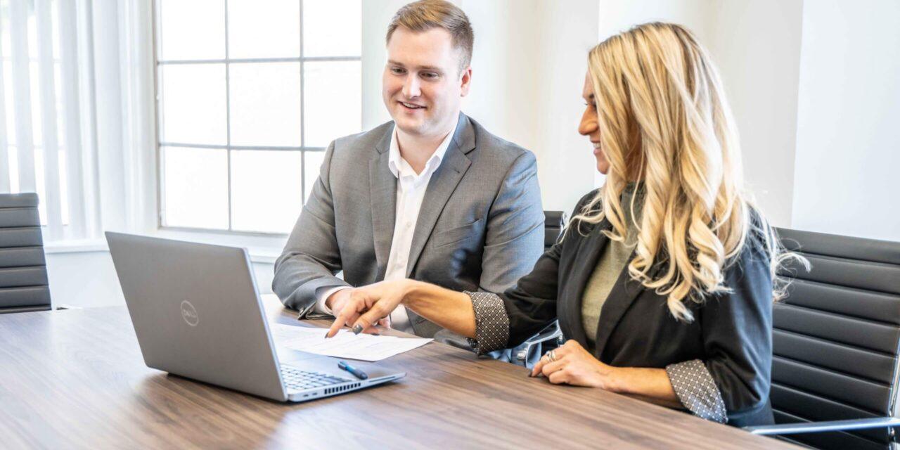 Two coworkers sitting at desk looking at computer