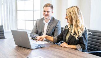 Two coworkers sitting at desk looking at computer
