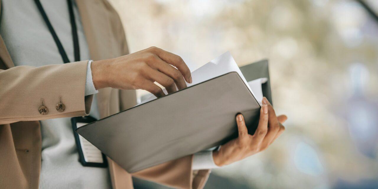 person holding a black folder with a year end checklist paper inside