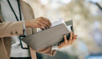 person holding a black folder with a year end checklist paper inside