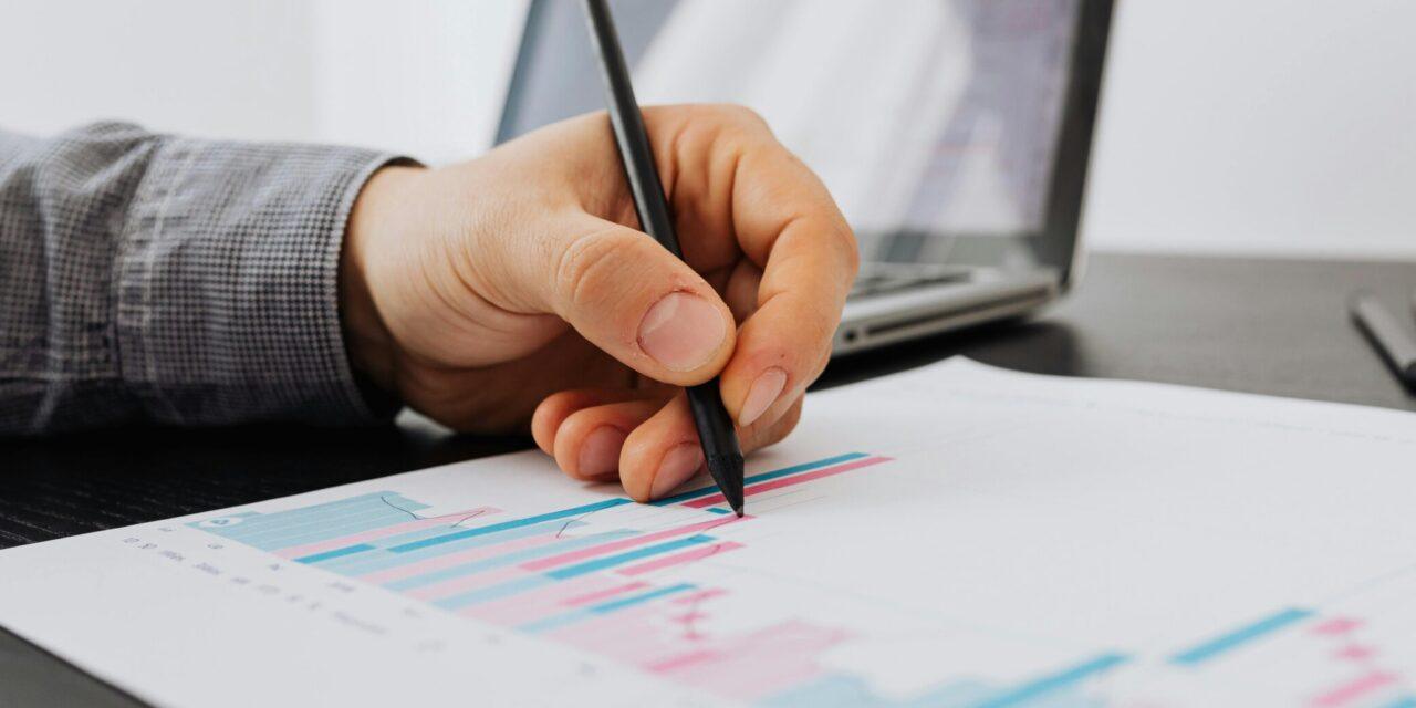 A person holding a pen and using it to mark up a printed out bar chart