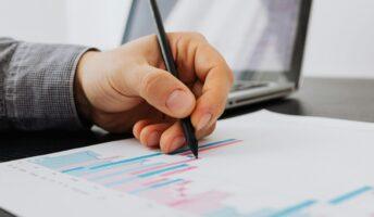 A person holding a pen and using it to mark up a printed out bar chart
