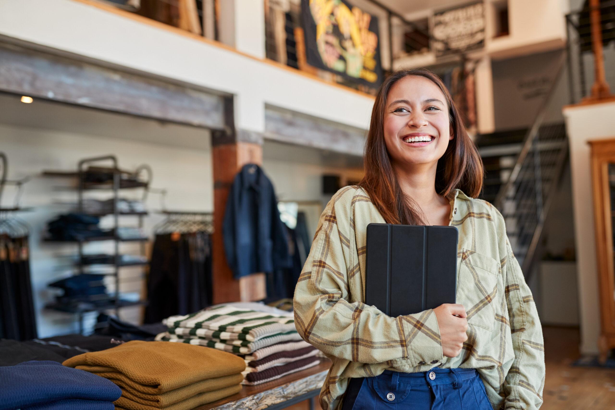 Smiling retail worker holding a tablet in a clothing store