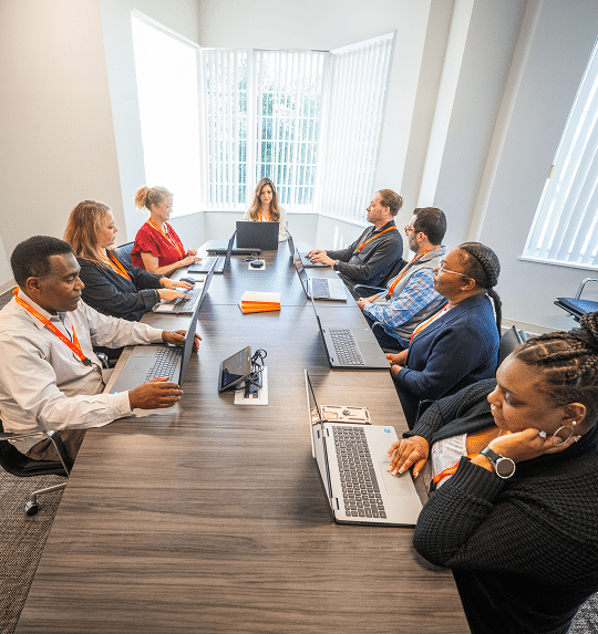 Staff seated around a long conference table with laptops
