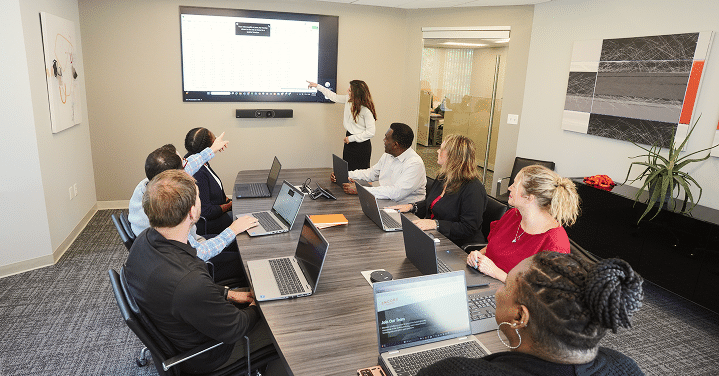 Team in a conference room watching a presentation on a wall screen